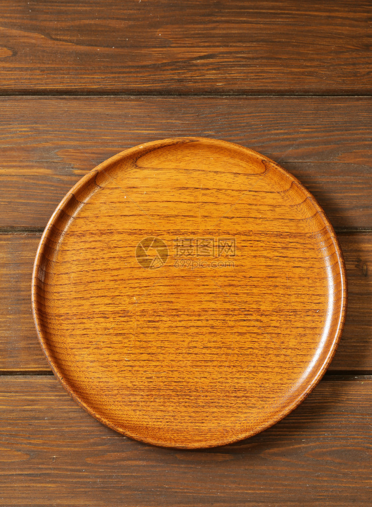 棕色木制背景上的木制空盘子图片