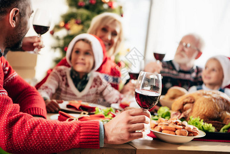 在圣诞节晚宴时和家人一起坐在桌边的红酒使人部图片
