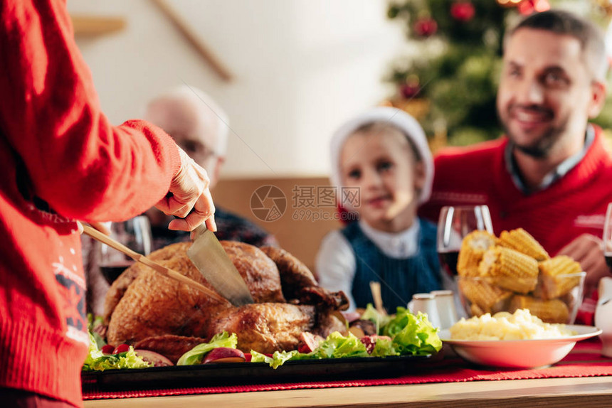 女在圣诞节晚宴上和幸福的家庭在家共进晚餐时切图片