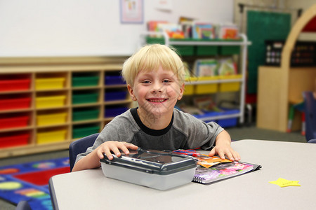 一名男孩在幼儿园教室的第一天上学时就坐在书桌旁图片