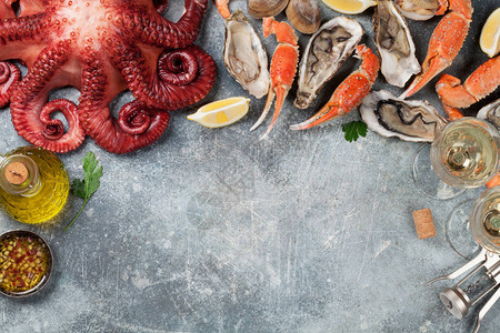海鲜八爪鱼龙虾蛤做饭在石桌上有白葡萄酒和文字空图片