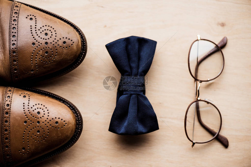 木制表面上的鞋子领带蝴蝶结和眼镜的顶部视图图片