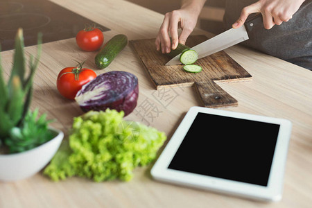 并使用带有食谱的数字平板电脑准备蔬菜沙拉样图片