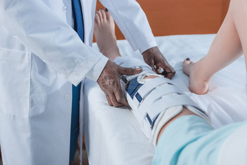 African美国医生在诊所受伤的病人腿上戴脚支图片