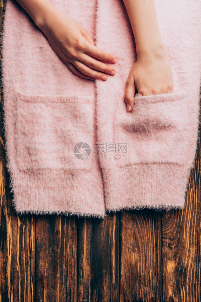 将粉红色毛衣的口袋放在木制桌顶图片