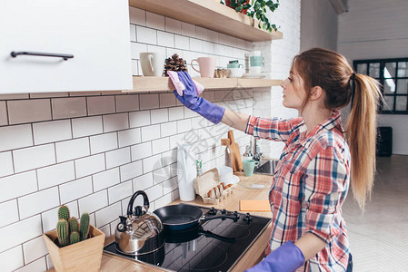 橡胶手套清洁厨柜的女人图片