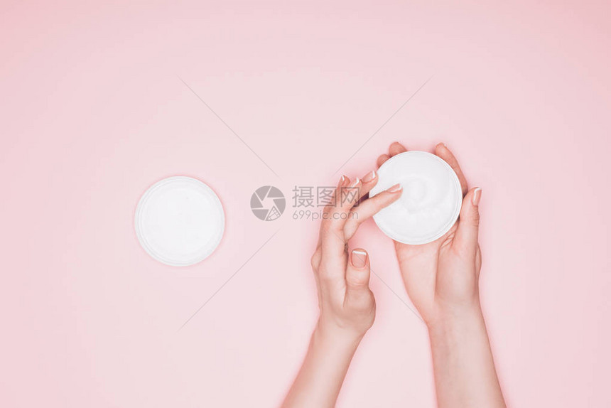 女从粉红色的罐子中取出保湿霜的短片图片