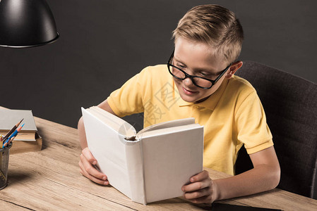 身戴眼镜的男学生在桌边用灯彩色铅笔和一堆灰图片