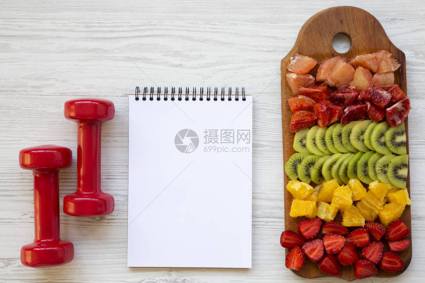 健康概念饮食计划切水果哑铃白木背景的记图片