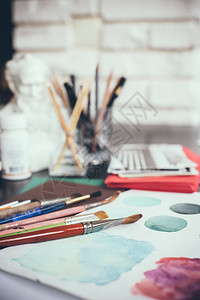 艺术家工作室的混点水彩油漆刷子和草图调色板和绘画工具设计师工作场图片