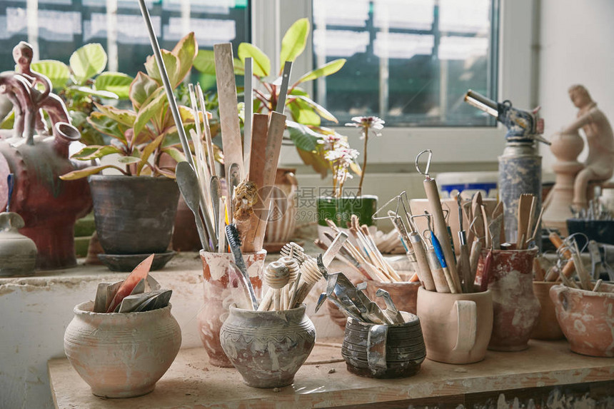 陶瓷工作室餐桌上陶器工具和油漆笔刷图片