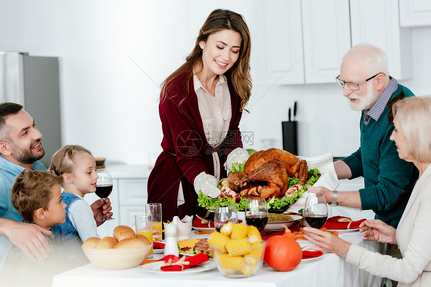 外祖父和成年女人带着烤火鸡做感恩节晚宴与图片