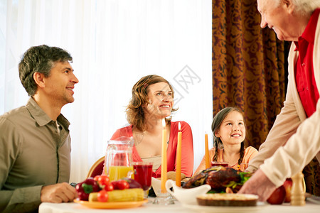 在感恩节晚宴上坐在桌边看老人的快乐家庭的肖像图片