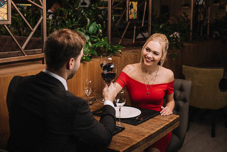 开心的姑娘喝红酒笑着在餐厅的男图片