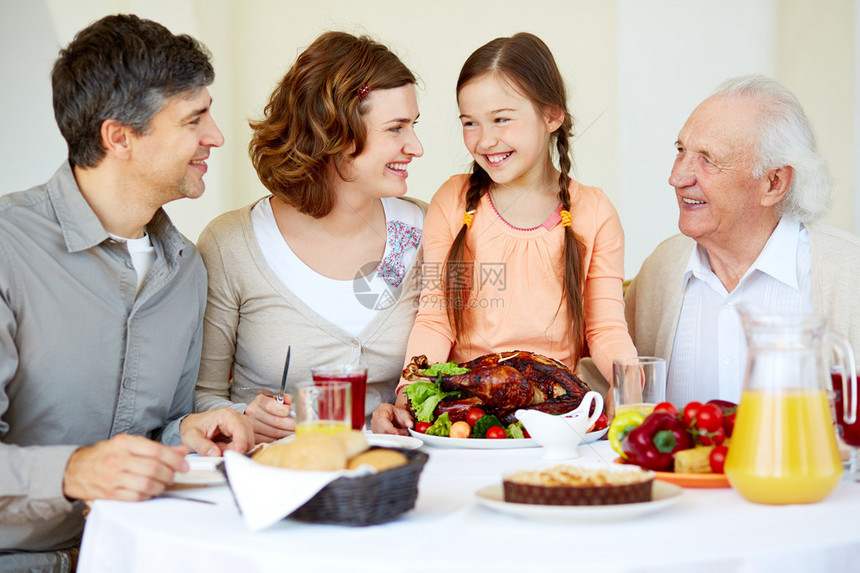 快乐家庭坐在节庆桌边吃着感恩图片