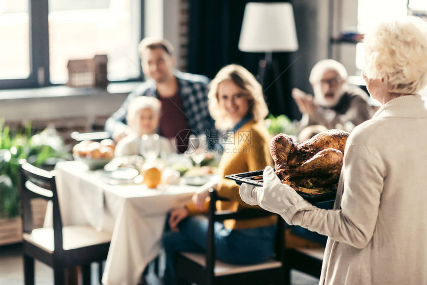 带着感恩节火鸡与家人共进节日晚餐的老妇人图片