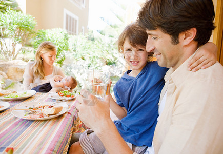四口人家庭在家门廊花园户外与母亲父亲女婴和一位男孩同父共饮用水图片