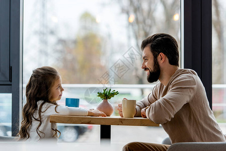 快乐的父亲和女儿坐在咖啡厅里图片