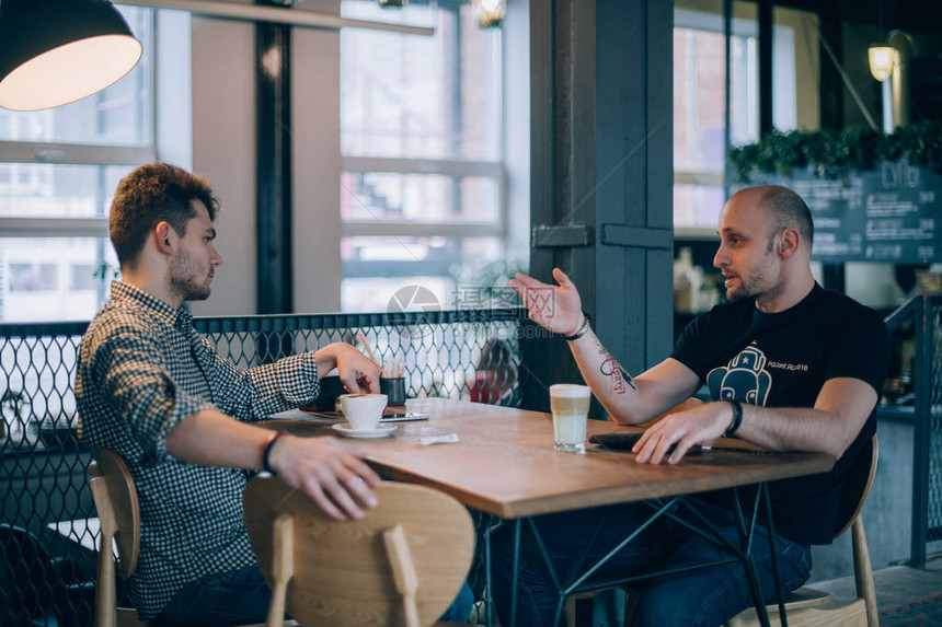 两个年轻人在咖啡馆里边喝咖啡边交流小伙子们在一家小餐馆的餐图片