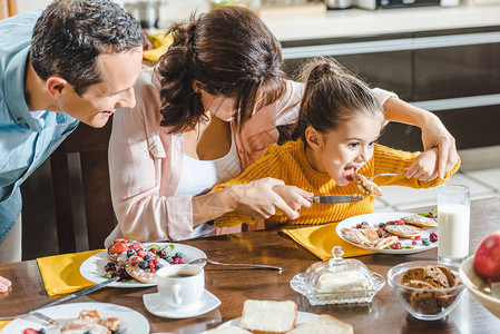 快乐的一家人一起吃煎饼餐桌上有浆果图片