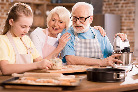 快乐的祖父母在厨房桌上看小姑娘花着钱图片