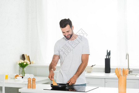 早上在厨房用抹刀和煎锅做饭的人图片