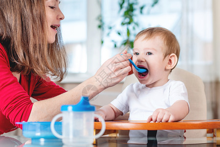 母亲在厨房里用汤匙粥给婴儿喂奶孩子吃健康食物时的情感如果孩子不吃的图片