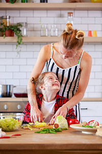 年轻母亲与女儿一起在公寓厨房切菜的画面图片