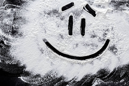 在抽象的黑色背景上的白色小麦面粉上的笑脸黑板或桌子上的顶视图烹图片