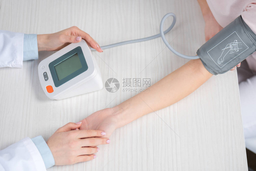 测量病人坐在桌子上的血压的医生图片