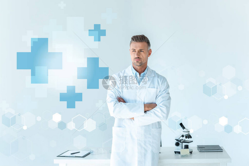 长相英俊的科学家站在十字臂靠近白与医疗标志隔离的图片