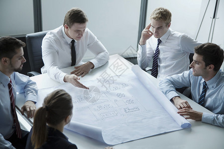 5名建筑师讨论和规划办公室蓝图图片
