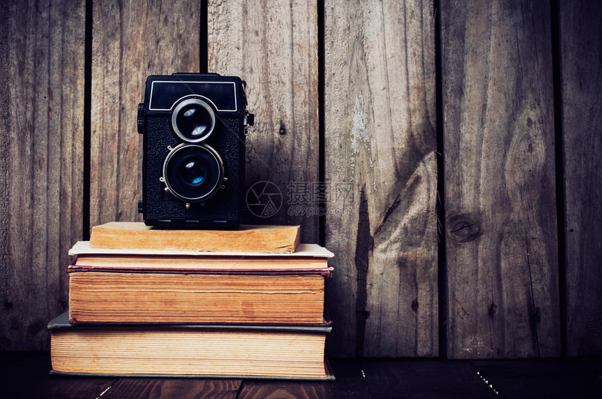 旧式中型摄影机和木板上的一堆书图片