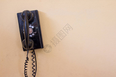 黑色古老董模拟电话拨号或滚动电话在旧墙上图片
