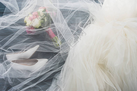 木深蓝色桌面上的一双鞋婚纱和花束的顶部视图图片