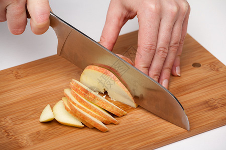 女人的手用厨房刀在木板上图片