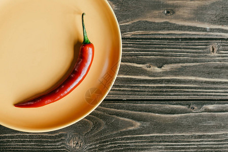 红辣椒放在木桌上的盘子里图片