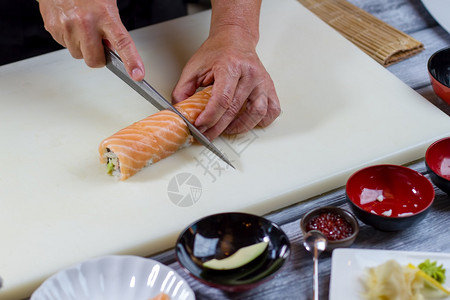 手握刀切寿司大寿司卷寿司厨师烹饪晚饭经证明图片