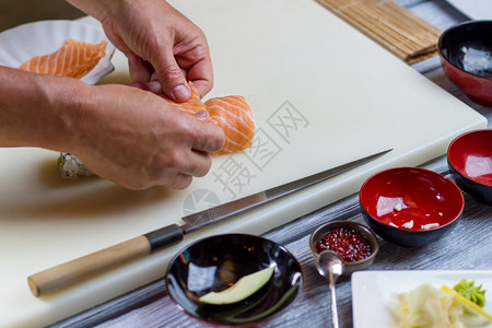 人手拿着寿司卷生鱼肉片乌拉木薯卷新鲜鲑鱼日本厨图片