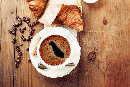 质朴的木质背景上的脆皮新鲜羊角面包和咖啡浓缩咖啡早餐顶视图片