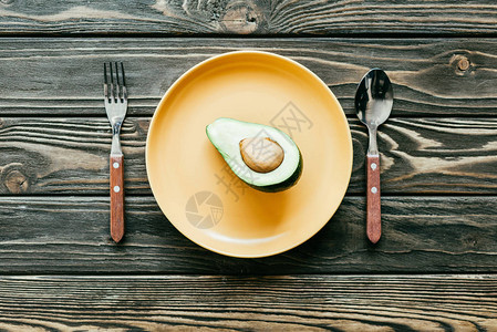 Avocado用勺子和叉子放在板上图片
