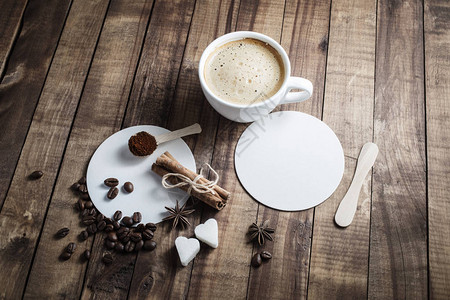 木桌背景上的咖啡咖啡杯肉桂棒咖啡豆茴香糖勺子和杯垫图片
