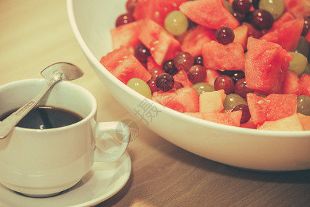 一杯咖啡和一碗新鲜水果放在图片