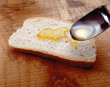 维珍橄榄油从勺子到新鲜面包中被冲洗图片