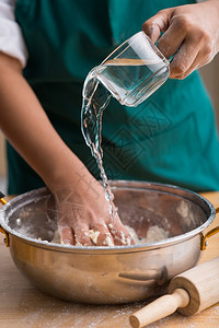 厨师的手用面粉把水倒进碗里特写图片
