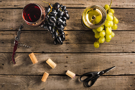 木桌上的红酒和白葡萄酒开瓶器软木塞和葡萄的酒图片