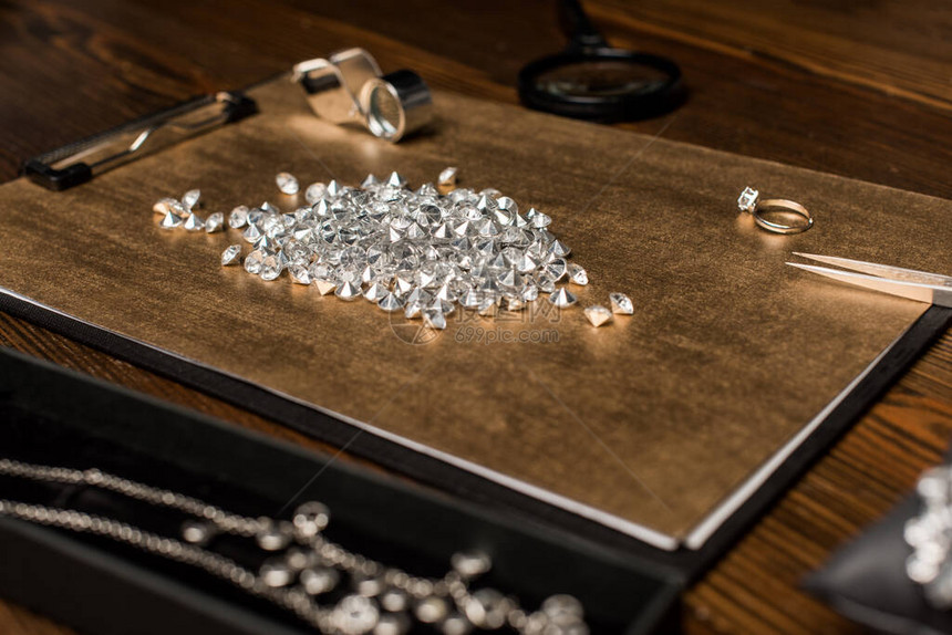 宝石放大镜和珠宝在木桌上的选择焦点图片