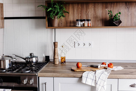 在现代厨房用钢炉锅刀在木制切菜板上烹饪食物图片