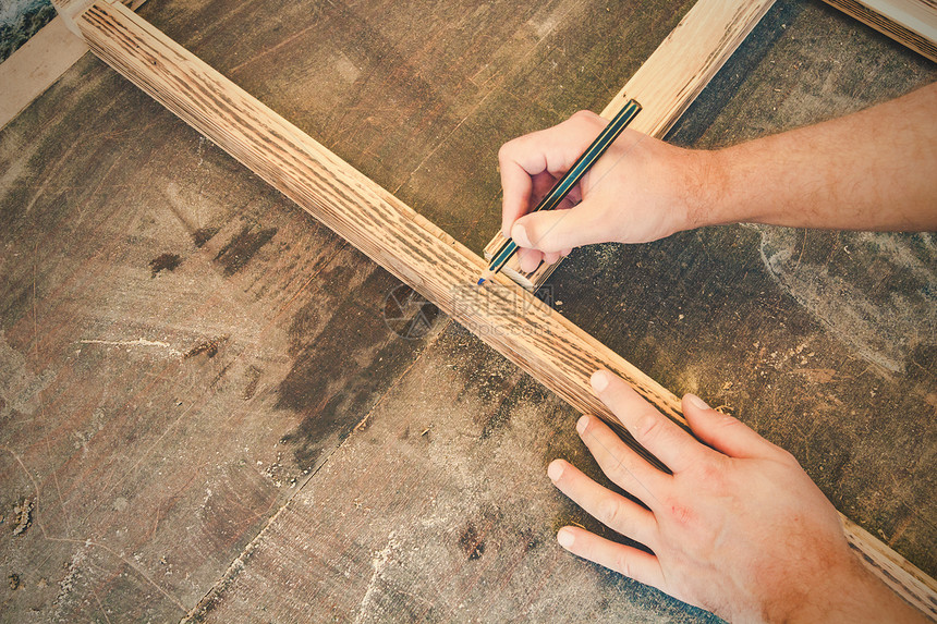 木匠用铅笔在旧木架上做记号图片