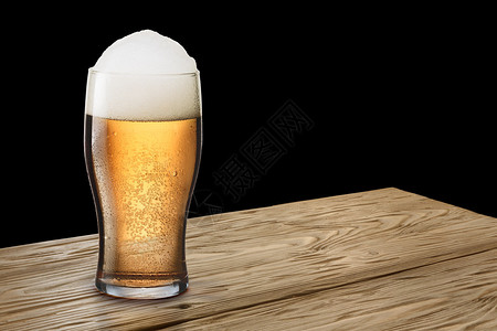 在木桌或吧台上放着一杯带有泡沫的清淡泡沫啤酒图片